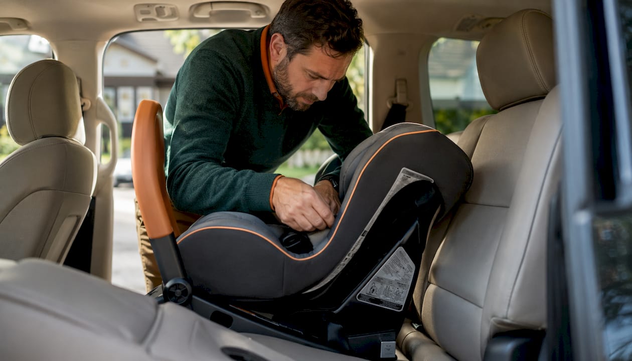 Parent adjusting child car seat in rental vehicle
