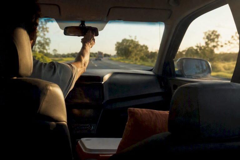 Driver’s hand on mirror on subtropical highway